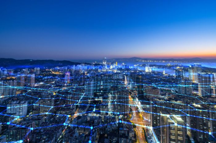 A cityscape during twilight with blue and white digital light trails overlaying the buildings