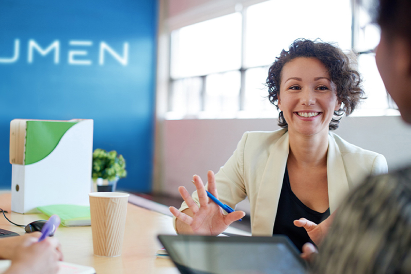 Businesswoman at Lumen office with tablet, talking with a coworker