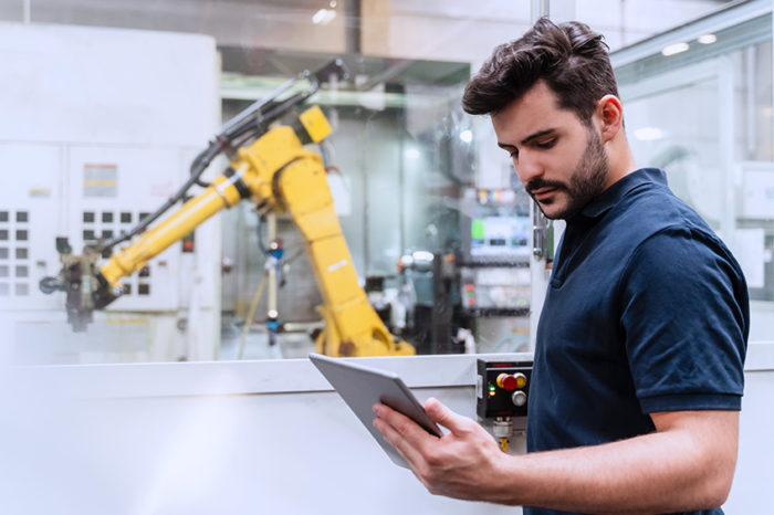 A man using a device works with robot