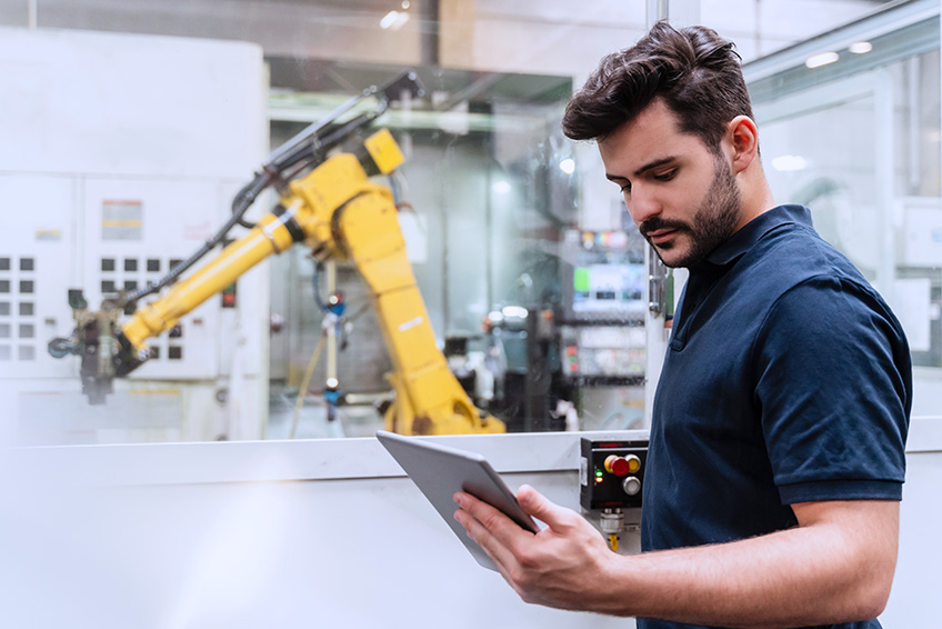 A man using a device works with robot