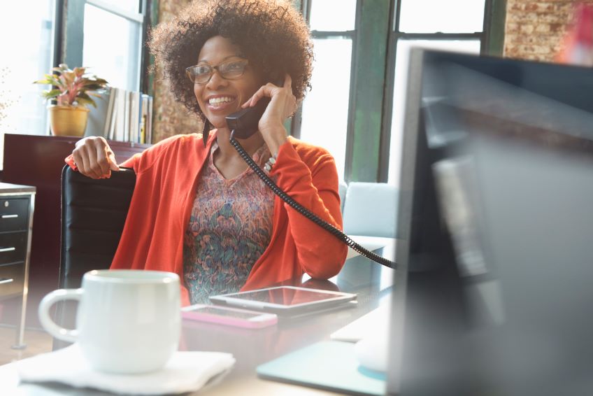 woman on phone at desk smiling