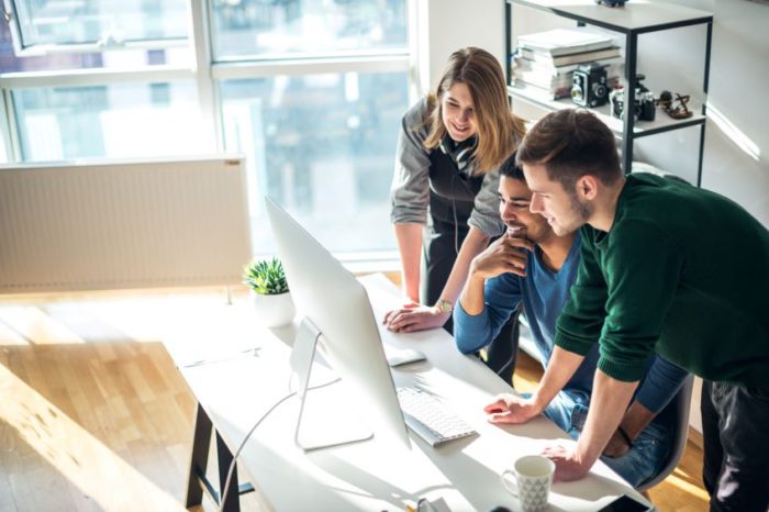 Three people gathered around a desktop computer