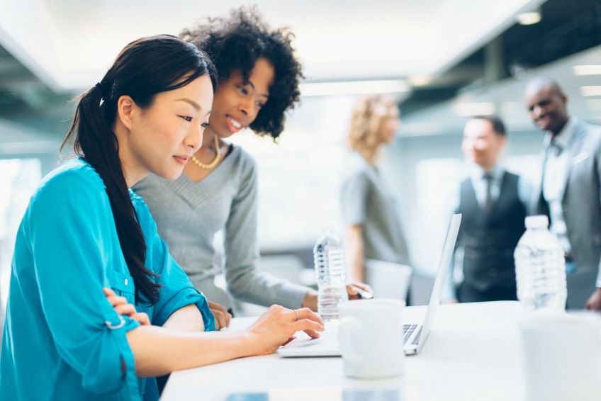 Two businesswomen looking at a laptop screen.