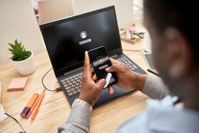 Man with a laptop and phone showing password is locked.