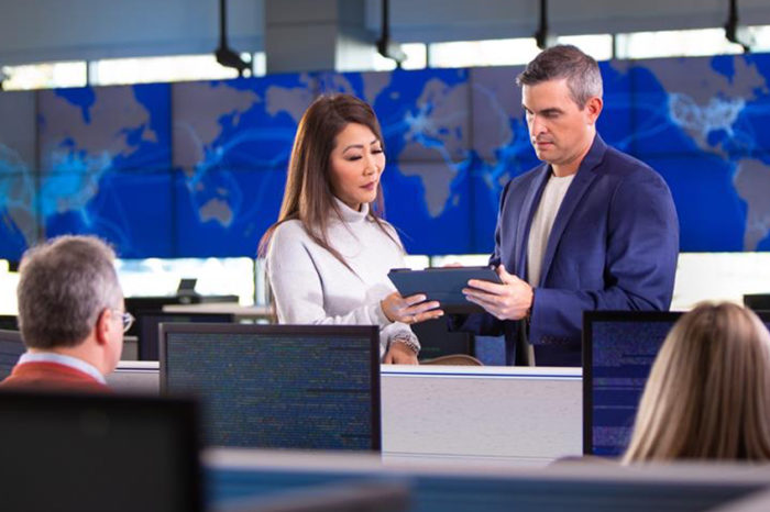 Team members talking at work stations