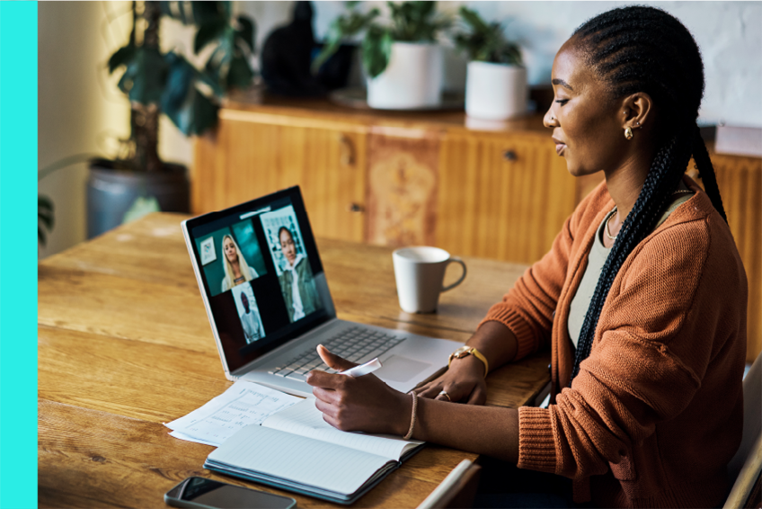 Woman works at her desk on a laptop while on a video call.