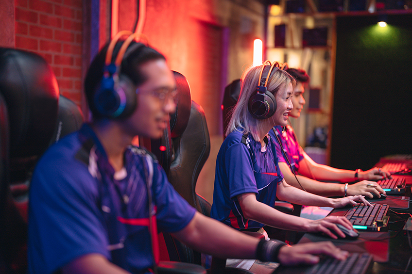 Gamers wearing headphones compete at an esports tournament