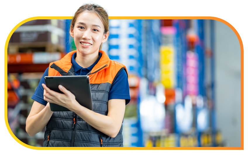 Woman stands inside a warehouse and works from her tablet